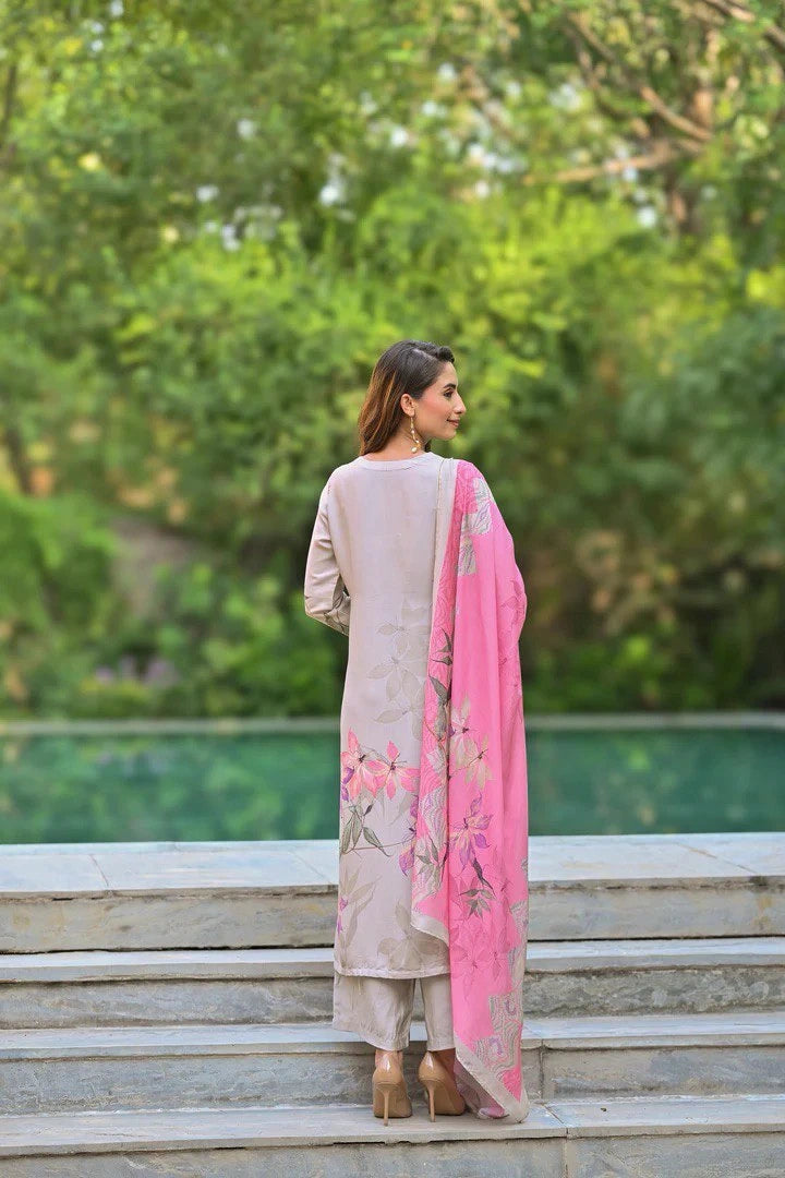Woman in a beige outfit with a pink scarf standing on steps outdoors